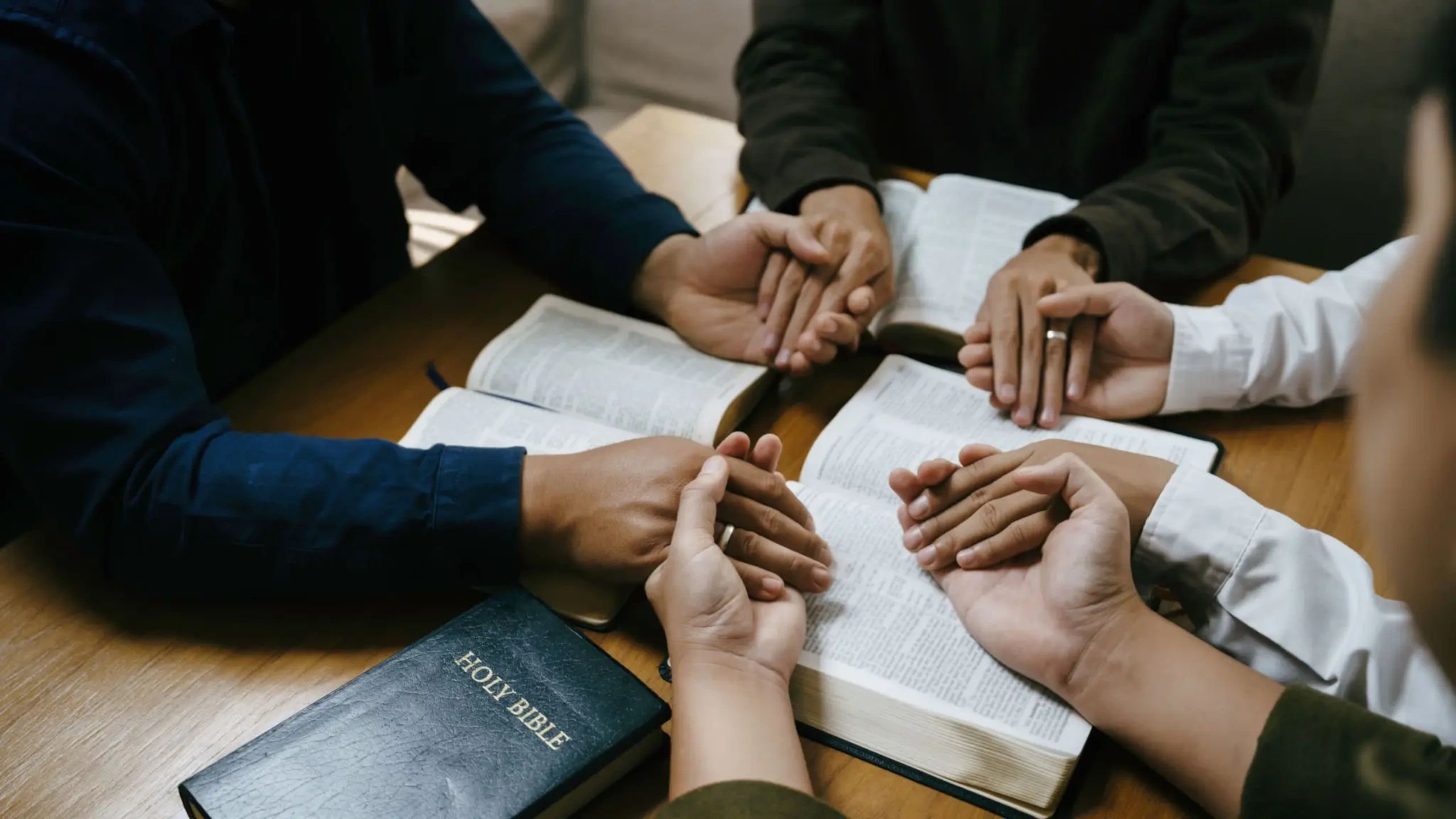 Hands joined over Bible in prayer